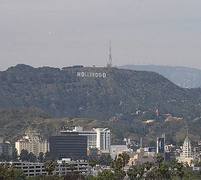 The Hollywood sign is seen on a hill.  Smog is in the air.